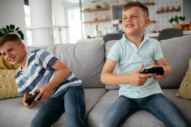 Video oyunu oynayan mutlu kardeşler. Küçük kardeşler oturma odasında video oyunu oynarken eğleniyorlar..