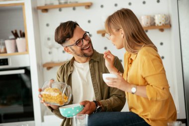 Genç çift evde kahvaltı hazırlıyor. Sevgi dolu çift mutfakta mısır gevreği yiyor..