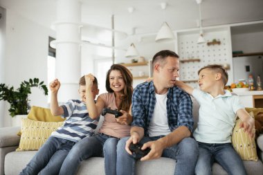 Karı koca oturma odasında joysticklerle oyun oynuyorlar. Sevgili çift evde çocuklarla video oyunu oynuyor..