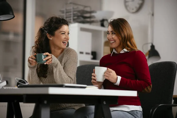 Happy businesswomen talking and laughing in open space office