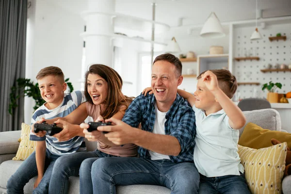 Husband and wife playing video games with joysticks in living room. Loving couple  playing video games with kids at home.