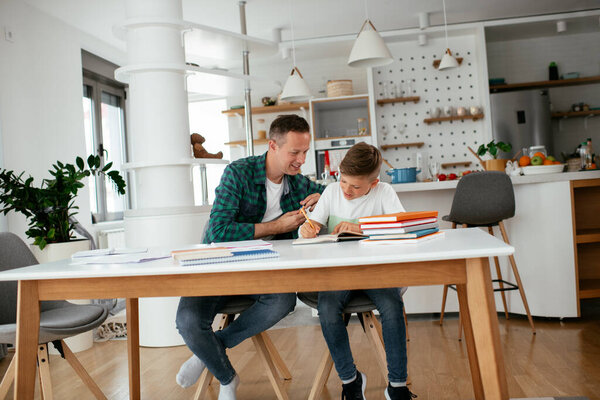 Father helping his son with homework at home. Little boy learning at home.