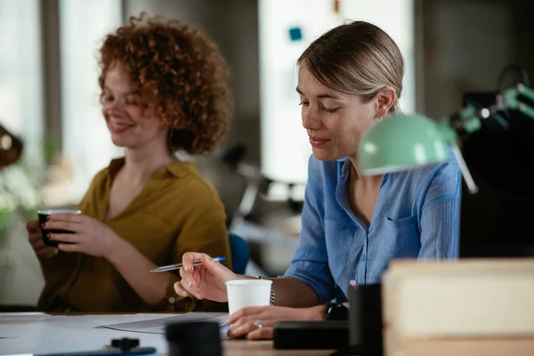 Businesswomen working on a new project. Colleagues discussing work in office.