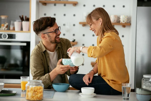 Genç çift evde kahvaltı hazırlıyor. Sevgi dolu çift mutfakta mısır gevreği yiyor..
