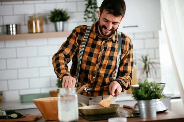 Mutfaktaki yakışıklı adamın portresi. Genç adam lezzetli yemekler hazırlıyor..