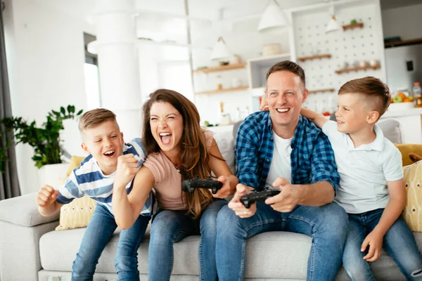 Husband and wife playing video games with joysticks in living room. Loving couple  playing video games with kids at home.