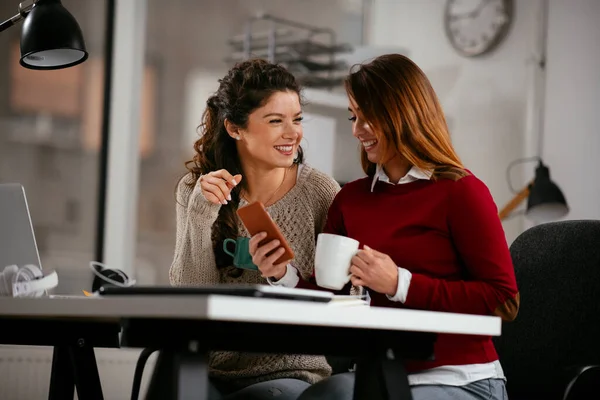 Happy businesswomen talking and laughing in open space office