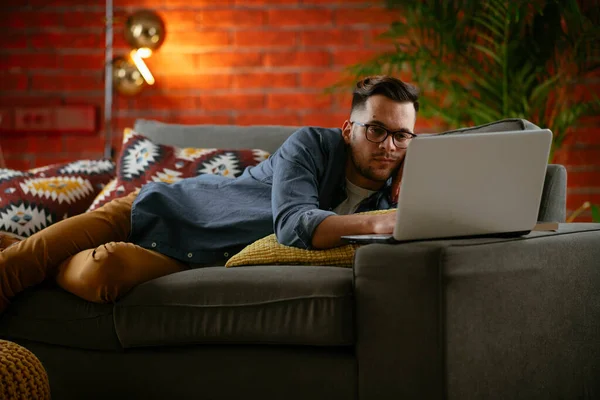 Man watching streaming series in a laptop computer at home.