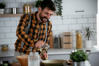 Mutfaktaki yakışıklı adamın portresi. Genç adam lezzetli yemekler hazırlıyor..