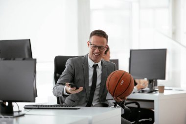 Ofiste basketbolla oynayan yakışıklı bir iş adamı. Genç işadamı çalışırken eğleniyor.
