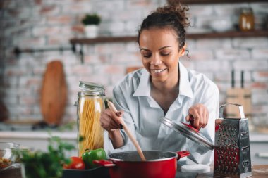 Güzel bir kadın yemek pişiriyor ve mutfakta eğleniyor. Kız mutfakta sağlıklı yemek pişiriyor..