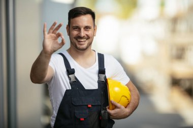Sokakta sarı kasklı yakışıklı bir işçinin portresi.