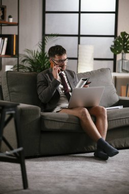 Evde pantolonsuz çalışan bir iş adamı. Genç adam video görüşmesi sırasında bilgisayarı kullanıyor..