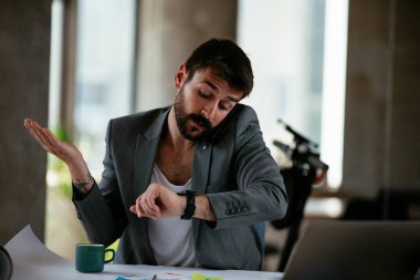İş adamı proje üzerinde çalışıyor. Genç işadamı ofiste akıllı telefondan konuşuyor..