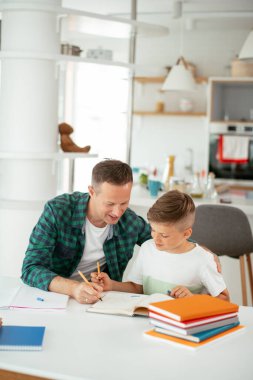 Baba, oğluna ev ödevinde yardım ediyor. Küçük çocuk evde öğreniyor..
