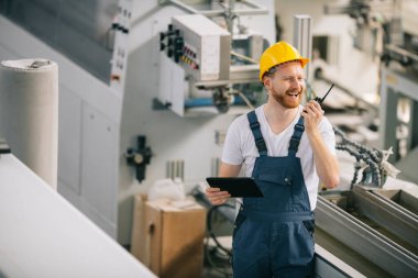 Üretim hattındaki fabrika işçisi. Fabrikada çalışan sarı kasklı adam..