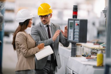 Fabrika müdürü ve mühendisi teftiş yapıyor. İş adamı ve işkadını üretim hattında.