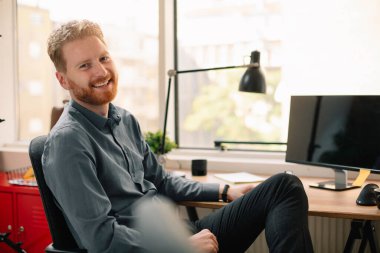 Ofiste çalışan bir iş adamı. Kızıl adam işyerinde oturuyor..