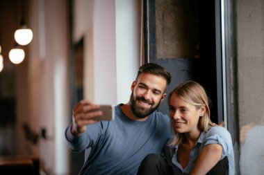 Genç ve güzel bir çift restoranda selfie çekiyor. 
