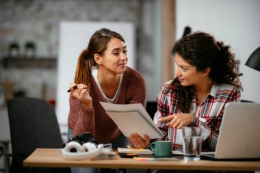 Açık uzay ofisinde konuşan ve gülen mutlu iş kadınları