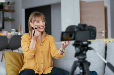Kadın video kaydedicisi, kanalı için makyaj dersi kaydediyor. Sosyal medyada paylaşmak için makyaj dersi alan genç ve güzel bir kadın..
