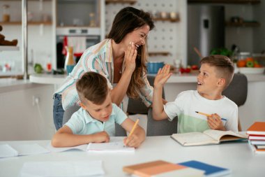 Anne oğullarıyla ödev yapıyor.