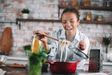 Güzel bir kadın yemek pişiriyor ve mutfakta eğleniyor. Kız mutfakta sağlıklı yemek pişiriyor..