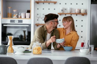 Genç çift evde kahvaltı hazırlıyor. Sevgi dolu çift mutfakta mısır gevreği yiyor..