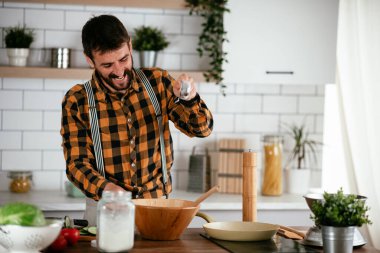 Mutfaktaki yakışıklı adamın portresi. Genç adam lezzetli yemekler hazırlıyor..