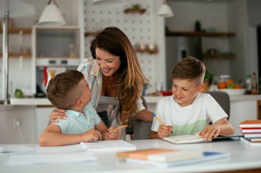 Anne oğullarıyla ödev yapıyor.