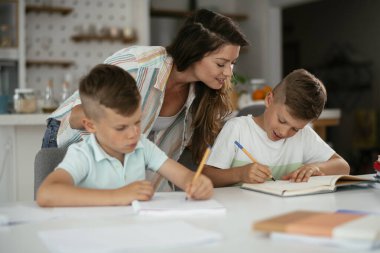 Anne oğullarıyla ödev yapıyor.