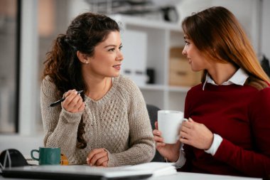 Açık uzay ofisinde konuşan ve gülen mutlu iş kadınları