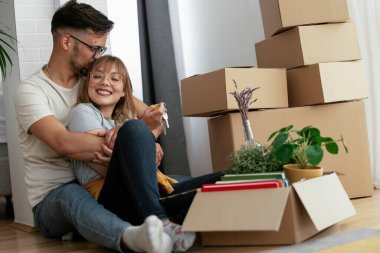 Yeni evde kutuların yanında kucaklaşan çift.