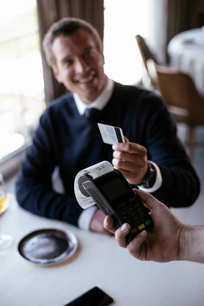 Businessman paying the bill with a credit card in restaurant.