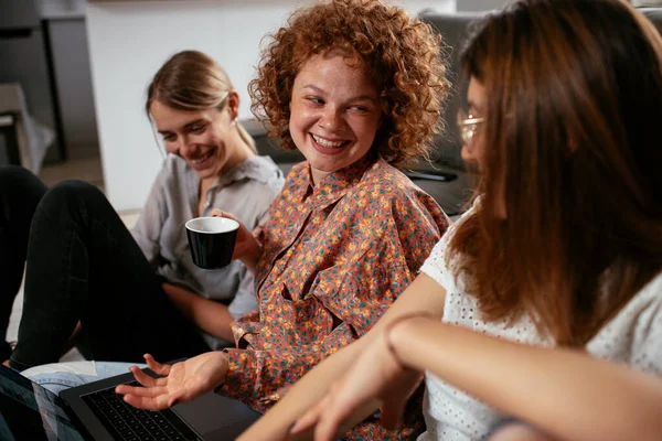 Girls talking and laughing in office. Beautiful women drinking coffee in the office