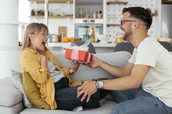 man presenting gift to woman at home