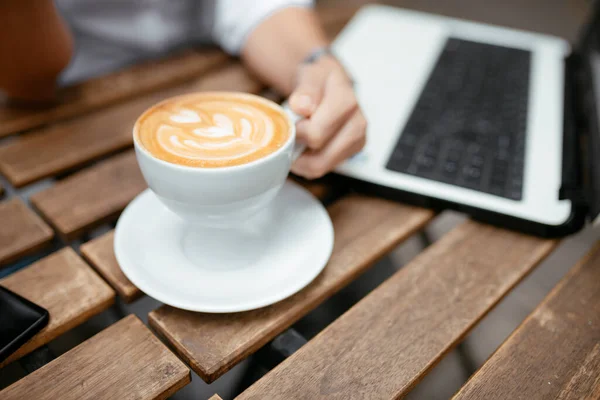 女性はノートパソコンを持ってカフェに座っている 女性の手ノートパソコンとコーヒーカップ — ストック写真