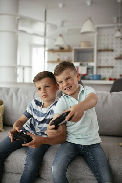 Video oyunu oynayan mutlu kardeşler. Küçük kardeşler oturma odasında video oyunu oynarken eğleniyorlar.