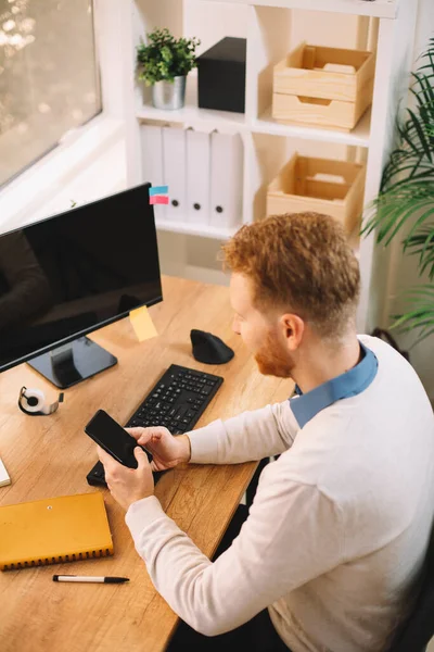 handsome businessman with ginger hair using smartphone in the office