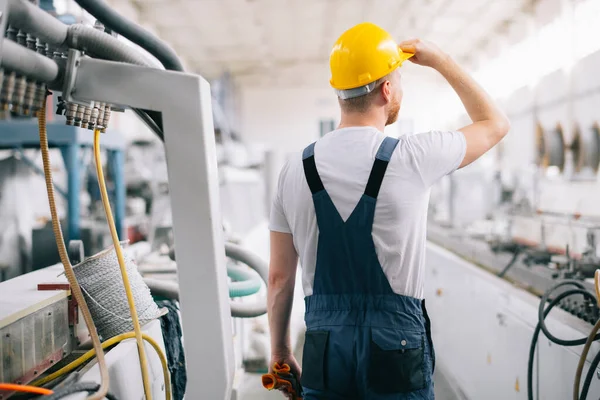 Üretim hattındaki fabrika işçisi. Fabrikada çalışan kasklı bir adam..