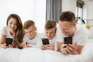 Cep telefonu kullanan bir aile. Aileler ve çocuklar evde akıllı telefon kullanıyorlar..