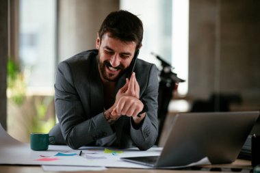 İş adamı proje üzerinde çalışıyor. Genç işadamı ofiste akıllı telefondan konuşuyor..