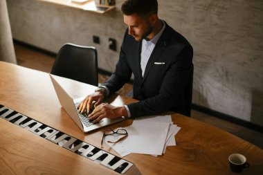 Ofiste dizüstü bilgisayarla çalışan bir iş adamı. Toplantı odasında iş süitinde bir adam var. Kağıt raporlarıyla şirket yöneticiliği.