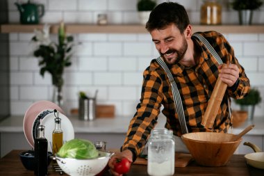 Mutfaktaki yakışıklı adamın portresi. Genç adam lezzetli yemekler hazırlıyor..
