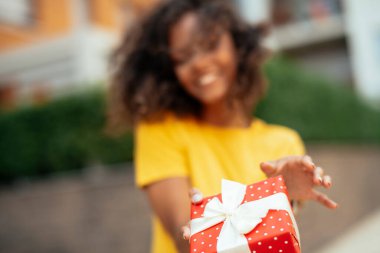 Genç Afrikalı bir kadın hediye veriyor.