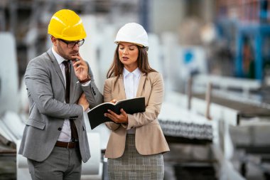 İşadamı ve iş kadını fabrikada iş konuşuyorlar.