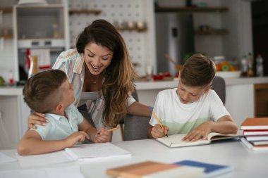 Anne oğullarıyla ödev yapıyor.