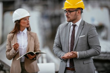 Fabrikadaki iş adamı ve iş kadını. Fabrika üretim hattında kalite kontrolde çalışan iki profesyonel insan..