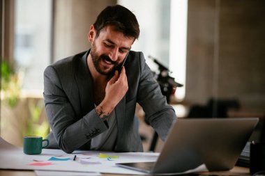 İş adamı proje üzerinde çalışıyor. Genç işadamı ofiste akıllı telefondan konuşuyor..