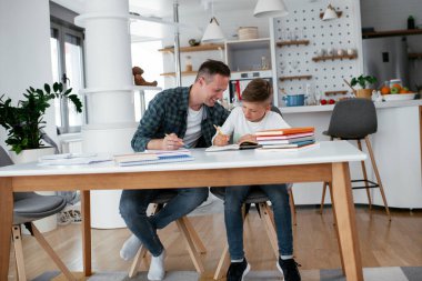 Baba, oğluna ev ödevinde yardım ediyor. Küçük çocuk evde öğreniyor..